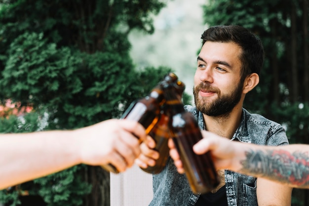 Gruppo di amici tintinnano le bottiglie di birra all&#39;aperto