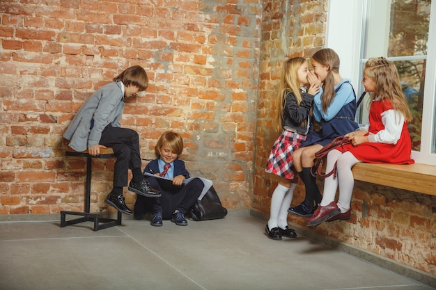 Gruppo di bambini che trascorrono del tempo insieme dopo la scuola. Amici belli che riposano dopo le lezioni prima di iniziare a fare i compiti. Interno loft moderno. Schooltime, amicizia, educazione, concetto di solidarietà.