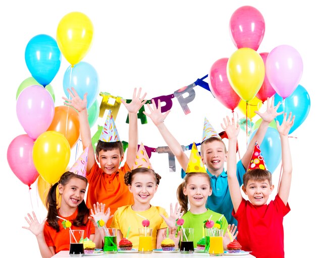 Gruppo di bambini in camicie colorate alla festa di compleanno con le mani alzate - isolato su un bianco.
