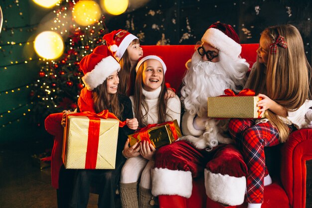 Gruppo di bambini seduti con santa e regali alla vigilia di Natale