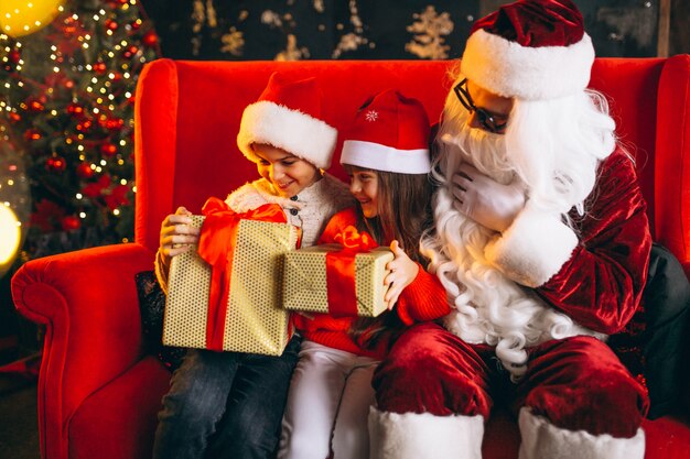 Gruppo di bambini seduti con santa e regali alla vigilia di Natale