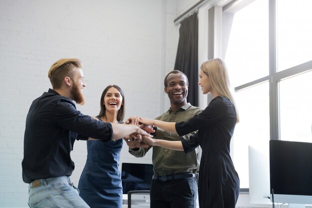 Gruppo di colleghi sorridenti che tengono le mani