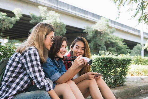 Gruppo di donne asiatiche che si siedono insieme e che guardano foto di controllo mentre viaggiando al parco