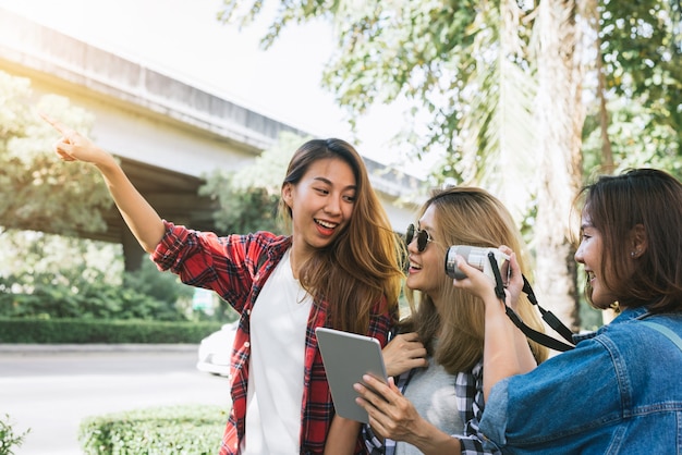 Gruppo di donne asiatiche che utilizzano la macchina fotografica per fare foto mentre si viaggia al parco in città urbana a Bangkok