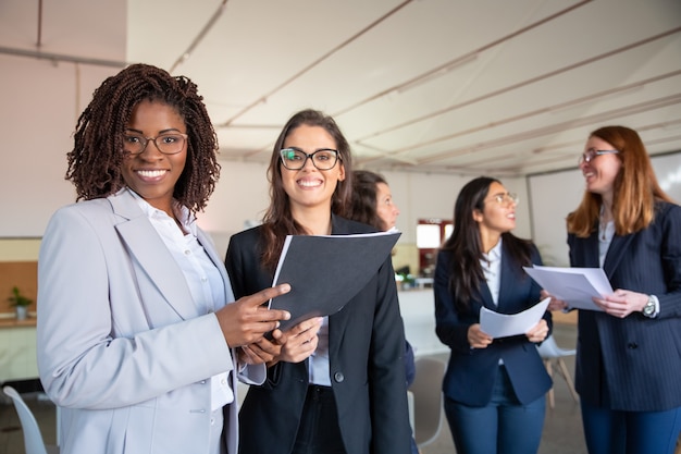 Gruppo di donne sorridenti che tengono i documenti cartacei