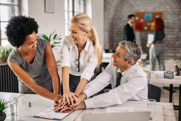 Gruppo di felici colleghi di lavoro che si tengono per mano in unità dopo un lavoro di successo Ci sono persone in background