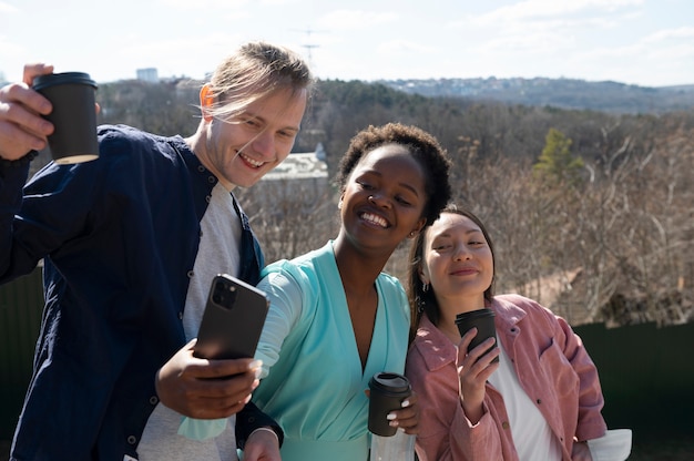 Gruppo di giovani amici che celebrano la revoca delle restrizioni sulla maschera facciale facendo un selfie al parco