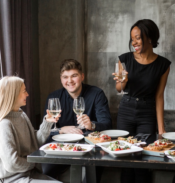 Gruppo di giovani amici che mangiano vino insieme