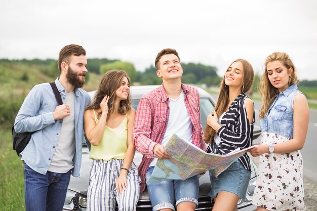 Gruppo di giovani amici in piedi davanti all&#39;automobile all&#39;aperto