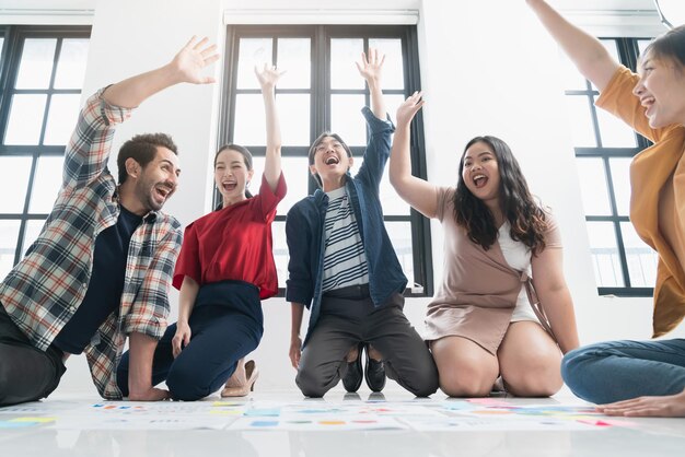 Gruppo di giovani creativi asiatici e caucasici felici godere ridere sorriso e grande successo emozione lavoro di squadra persone avvio affari imprenditore casual brainstorming riunione d'affari ufficio sfondo