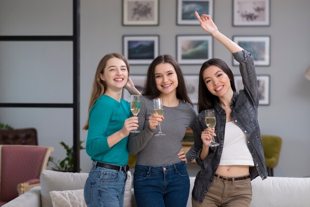 Gruppo di giovani donne che mangiano champagne a casa