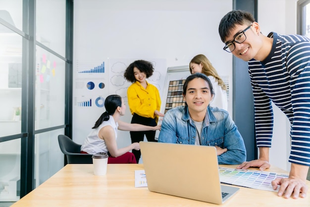 Gruppo di giovani imprenditori asiatici creativi felici su uno sfondo di ufficio per riunioni di lavoro Una buona leadership e lavoro di squadra portano al successo