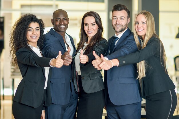Gruppo di imprenditori con il pollice gesto in ufficio moderno. Persone multietniche che lavorano insieme. Concetto di lavoro di squadra.