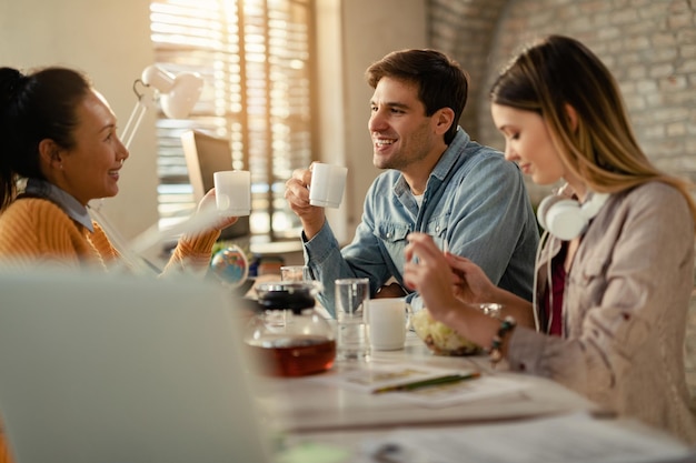 Gruppo di imprenditori felici che si divertono in pausa pranzo e comunicano in ufficio