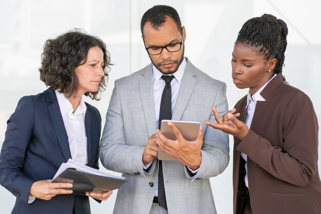 Gruppo di lavoro serio che legge e che discute rapporto di progetto