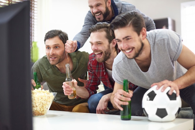 Gruppo di migliori amici che guardano la partita in TV