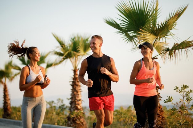 Gruppo di persone atletiche sorridenti che corrono insieme all'aperto.