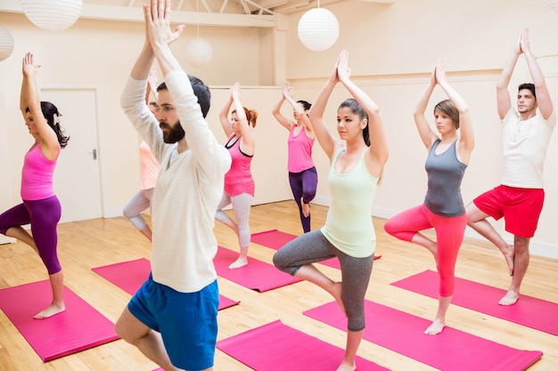 Gruppo di persone che svolgono esercizio yoga albero posa