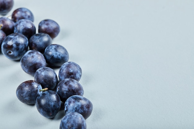 Gruppo di prugne fresche su sfondo blu