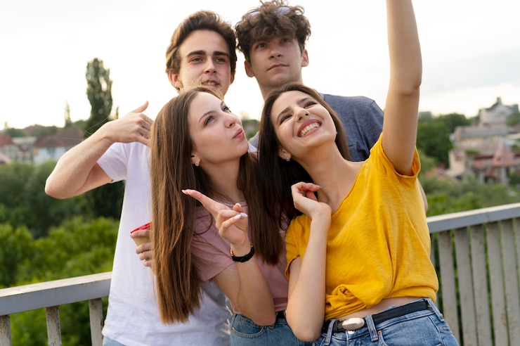 Foto gratuito gruppo di quattro amici che trascorrono del tempo insieme all'aperto e si fanno selfie