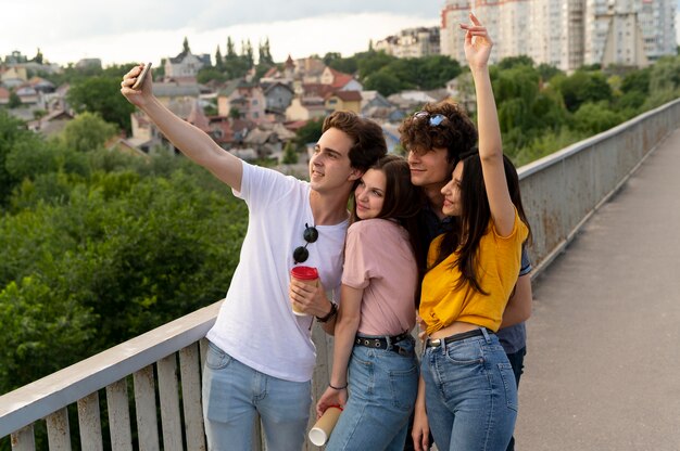 Gruppo di quattro amici che trascorrono del tempo insieme all'aperto e si fanno selfie