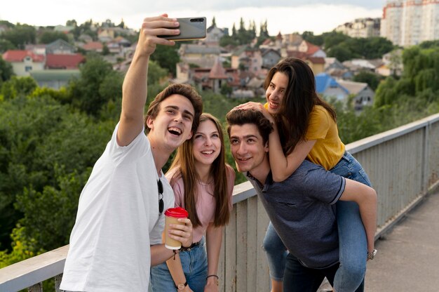 Gruppo di quattro amici che trascorrono del tempo insieme all'aperto e si fanno selfie