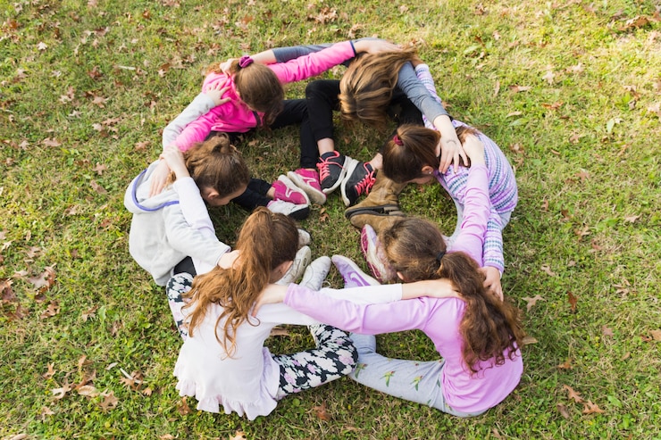 Foto gratuito gruppo di ragazze che si siedono insieme nella calca su erba verde