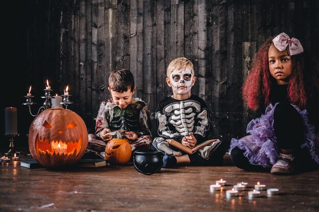 Gruppo di simpatici bambini multirazziali in costumi spaventosi durante la festa di Halloween in una vecchia casa. Concetto di Halloween.