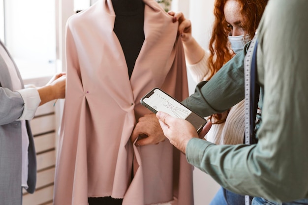 Gruppo di stilisti che lavorano in atelier e controllano l'indumento sulla forma del vestito