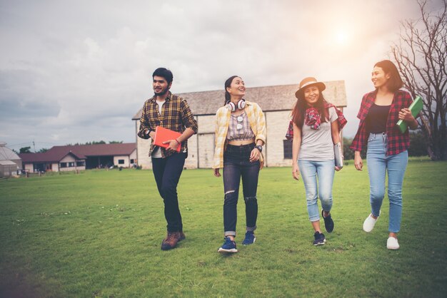 Gruppo di studenti a piedi attraverso il parco dopo le lezioni. Divertiti a parlare insieme.