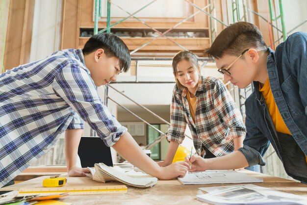 Gruppo di team di progettazione d'interni di architetti asiatici intelligenti che si consultano con l'ingegnere di costruzione lavoro brainstrom incontro con progetto di casa progetto e mockup di casa in casa struttura di ristrutturazione sfondo