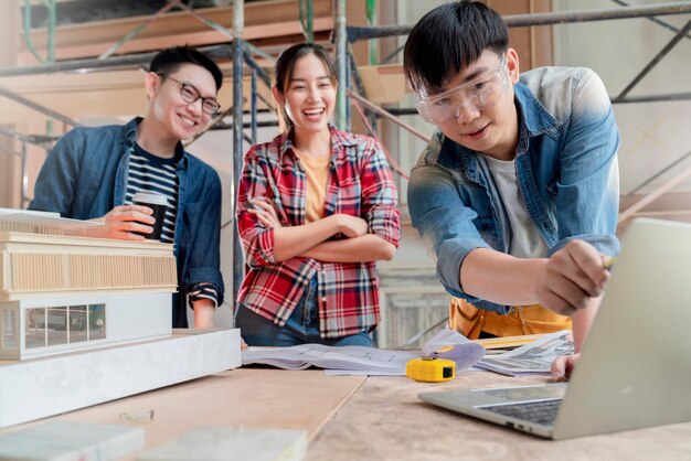 Gruppo di team di progettazione d'interni di architetti asiatici intelligenti che si consultano con l'ingegnere di costruzione lavoro brainstrom incontro con progetto di casa progetto e mockup di casa in casa struttura di ristrutturazione sfondo