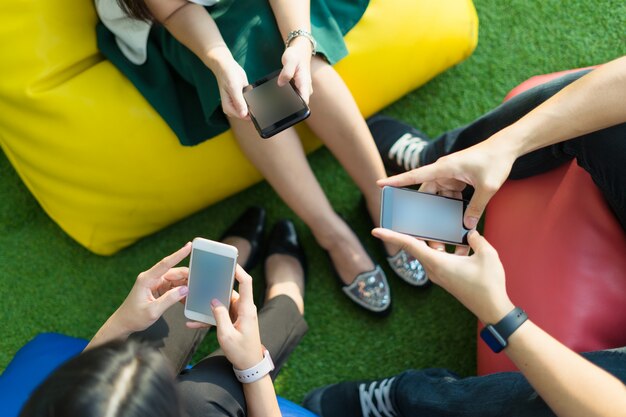 Gruppo di tre giovani che utilizzano smartphone insieme, moderno stile di vita o tecnologia di comunicazione gadget concetto.