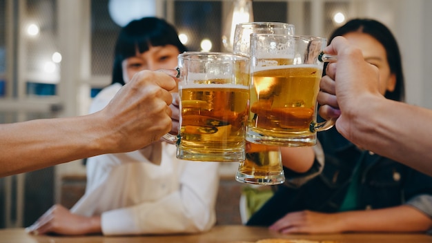 Gruppo di turisti felici giovani amici asiatici che bevono alcolici o birra artigianale e fanno festa in un night club al Khao San Road.