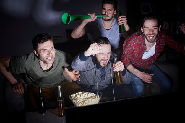 Gruppo di uomini che bevono birra e guardano il calcio in TV