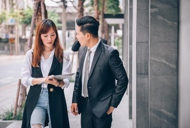 Gruppo di uomini d'affari asiatici nel quartiere degli affari che parlano di nuovi affari ed economici in una posizione all'aperto