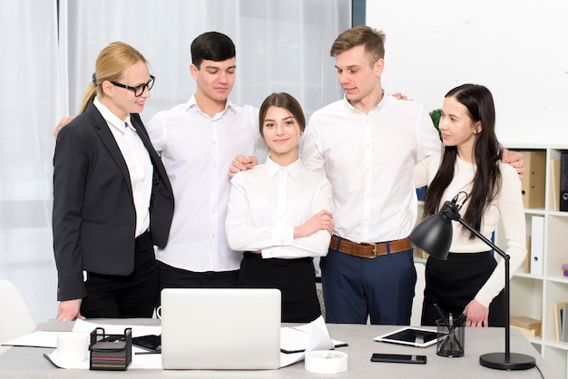 Gruppo di uomini d&#39;affari guardando il suo collega femmina in piedi dietro la scrivania in ufficio