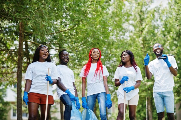 Gruppo di volontari africani felici con area di pulizia dei sacchi della spazzatura nel parco Africa volontariato di beneficenza e concetto di ecologia