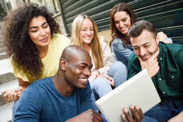 Gruppo multietnico di giovani che esaminano un computer tablet