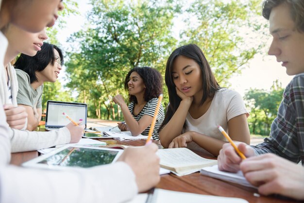 Gruppo multietnico di giovani studenti seduti e studiando