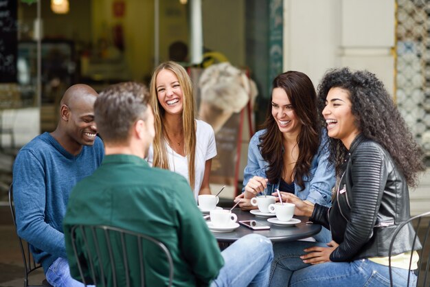 Gruppo multirazziale di cinque amici che hanno un caffè insieme