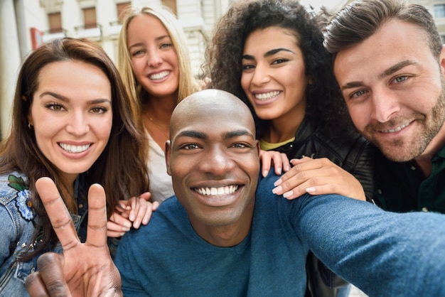 Gruppo multirazziale di giovani che prendono selfie