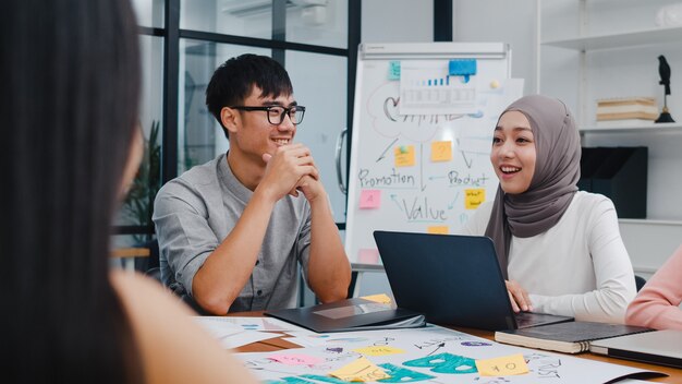 Gruppo multirazziale di giovani creativi in abbigliamento casual intelligente che discutono di idee di incontro di brainstorming aziendale progetto di progettazione di software per applicazioni mobili in un ufficio moderno.