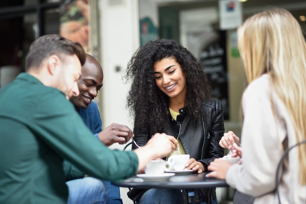 Gruppo multirazziale di quattro amici che hanno un caffè insieme