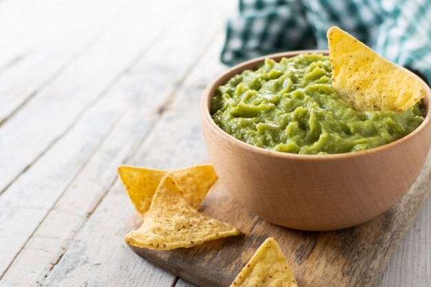 Guacamole messicano con chip nacho in ciotola di legno su tavola di legno rustica FoodxA messicano tradizionale