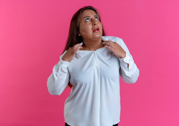 Guardando il colletto della camicia della holding della donna di mezza età caucasica casuale impressionato