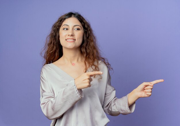 Guardando il lato sorridente la giovane ragazza graziosa indica a lato