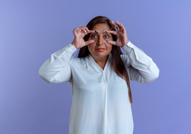 guardando la fotocamera casual indoeuropea donna di mezza età opents con gli occhi delle dita