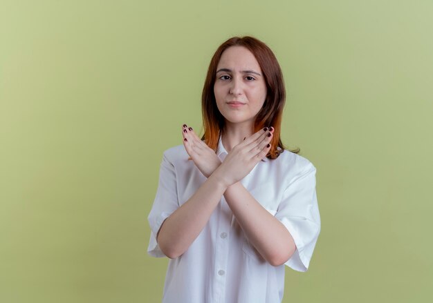 Guardando la fotocamera giovane ragazza rossa che mostra il gesto di non isolato su sfondo verde oliva