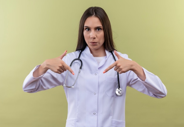 Guardando la giovane ragazza medico che indossa l'abito medico stetoscopio si punta su sfondo verde